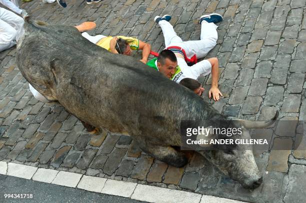 Participants fall next to a Cebada Gago fighting bull on the third day of the San Fermin bull run festival in Pamplona, northern Spain on July 9,...