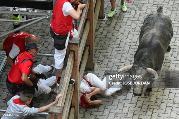 Participants fall next to a Cebada Gago fighting bull on the third day of the San Fermin bull run festival in Pamplona, northern Spain on July 9,...