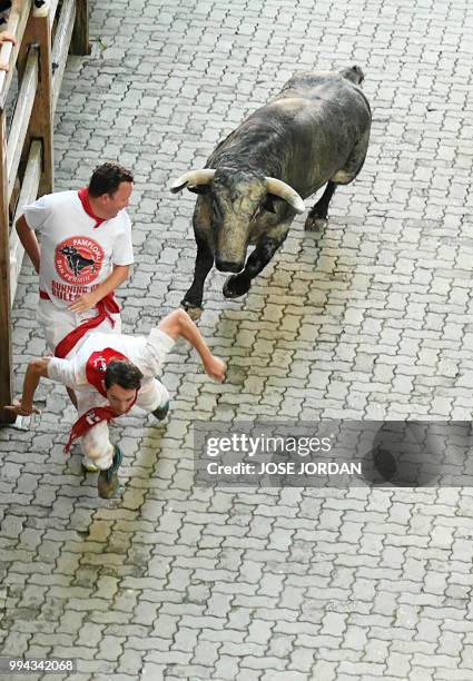 Participants fall next to a Cebada Gago fighting bull on the third day of the San Fermin bull run festival in Pamplona, northern Spain on July 9,...