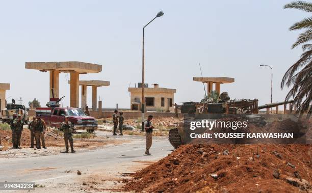 Syrian government soldiers stand by a tank and armed pickup trucks at the Nassib border crossing with Jordan in the southern province of Daraa on...