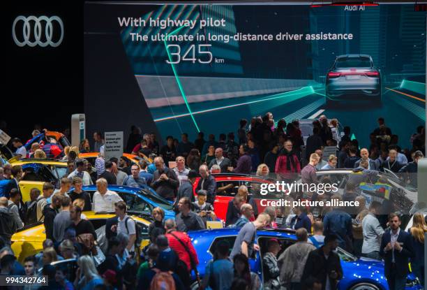 Visitors take a look at the vehicles of automobile manufacturer Audi while a commercial can be seen in the background in Frankfurt am Main, Germany,...