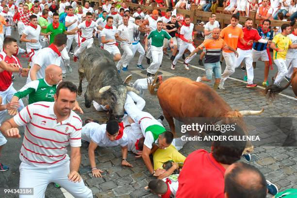 Participants fall next to Cebada Gago fighting bulls on the third day of the San Fermin bull run festival in Pamplona, northern Spain on July 9,...