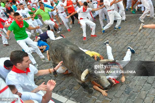 Participants fall next to a Cebada Gago fighting bull on the third day of the San Fermin bull run festival in Pamplona, northern Spain on July 9,...