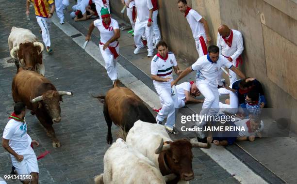 Participants fall next to Cebada Gago fighting bulls on the third day of the San Fermin bull run festival in Pamplona, northern Spain on July 9,...