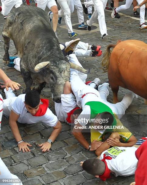 Participants fall next to a Cebada Gago fighting bull on the third day of the San Fermin bull run festival in Pamplona, northern Spain on July 9,...