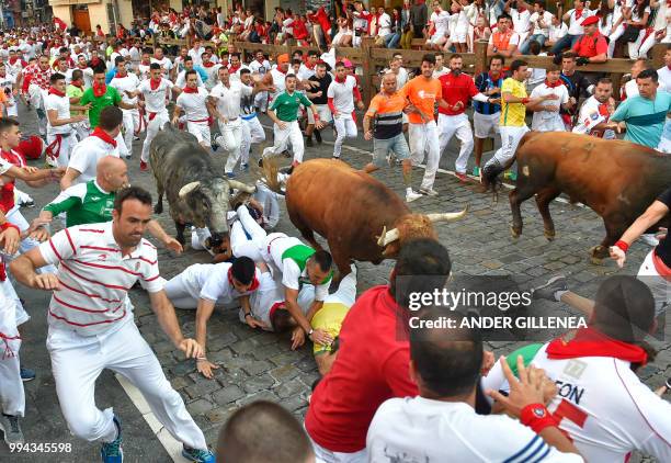 Participants fall next to Cebada Gago fighting bulls on the third day of the San Fermin bull run festival in Pamplona, northern Spain on July 9,...