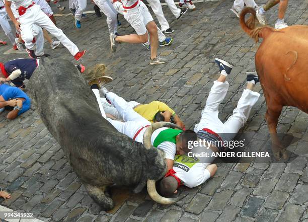 Participants fall next to Cebada Gago fighting bulls on the third day of the San Fermin bull run festival in Pamplona, northern Spain on July 9,...