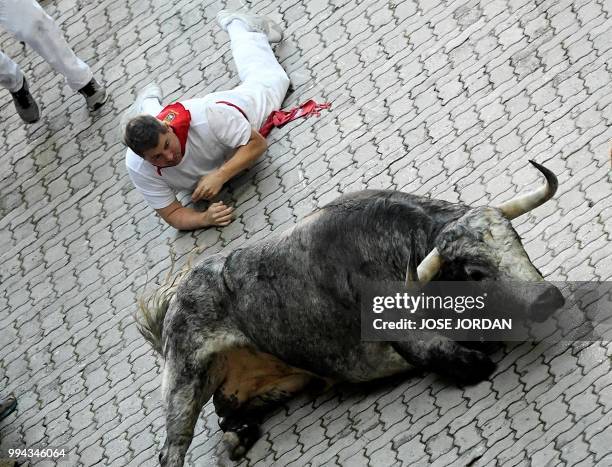 Participant and a Cebada Gago fighting bull fall on the third day of the San Fermin bull run festival in Pamplona, northern Spain on July 9, 2018. -...