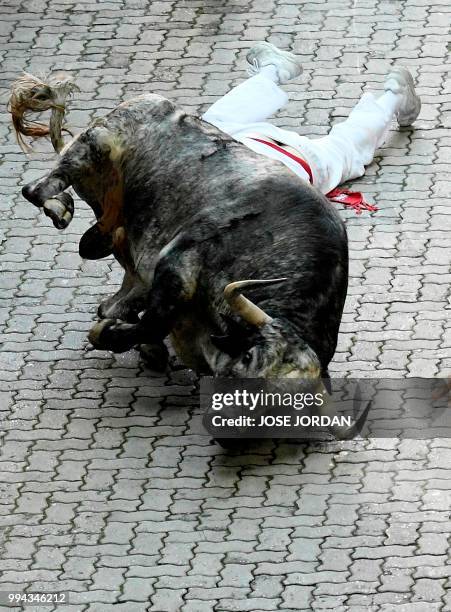 Participant and a Cebada Gago fighting bull fall on the third day of the San Fermin bull run festival in Pamplona, northern Spain on July 9, 2018. -...