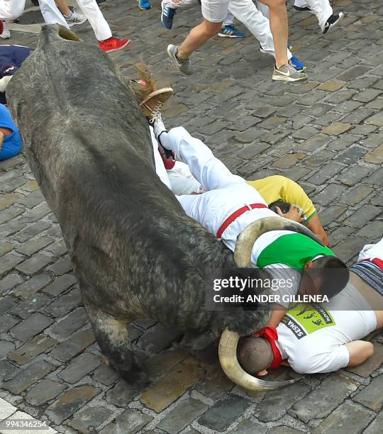 Participants fall next to Cebada Gago fighting bull on the third day of the San Fermin bull run festival in Pamplona, northern Spain on July 9, 2018....