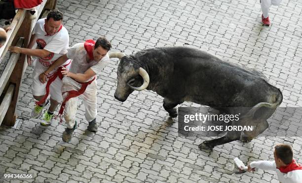 Participants run next to Cebada Gago fighting bull on the third day of the San Fermin bull run festival in Pamplona, northern Spain on July 9, 2018....