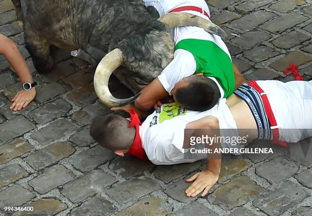 Participants fall next to Cebada Gago fighting bull on the third day of the San Fermin bull run festival in Pamplona, northern Spain on July 9, 2018....