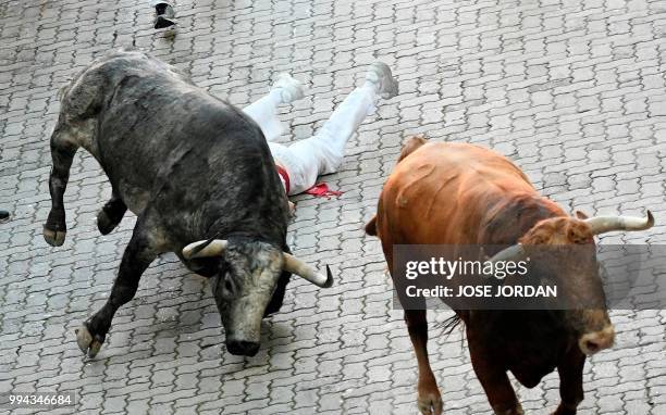 Participant falls next to Cebada Gago fighting bulls on the third day of the San Fermin bull run festival in Pamplona, northern Spain on July 9,...