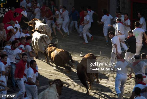 Participants fall next to Cebada Gago fighting bulls on the third day of the San Fermin bull run festival in Pamplona, northern Spain on July 9,...