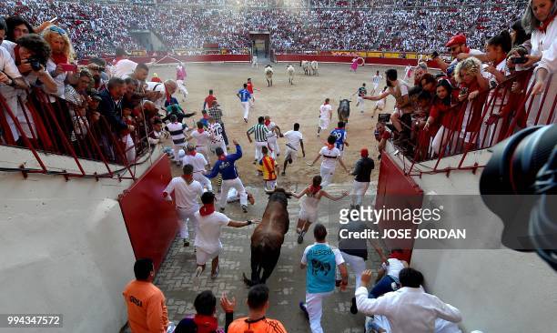 Participants enter the bullring with a Cebada Gago fighting bull on the third day of the San Fermin bull run festival in Pamplona, northern Spain on...