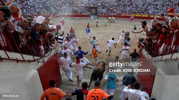 Participants enter the bullring with a Cebada Gago fighting bull on the third day of the San Fermin bull run festival in Pamplona, northern Spain on...
