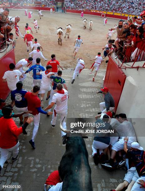 Participants enter the bullring with a Cebada Gago fighting bull on the third day of the San Fermin bull run festival in Pamplona, northern Spain on...