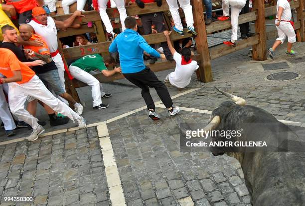 Participants run in front of a Cebada Gago fighting bull on the third day of the San Fermin bull run festival in Pamplona, northern Spain on July 9,...