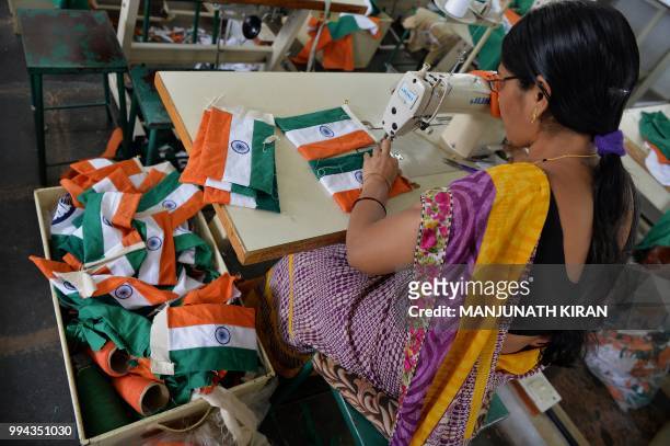 This photo taken on May 9, 2018 shows an employee of Khadi Gramodyog Samyukta Sangh stitching together an Indian national flag at the Indian National...