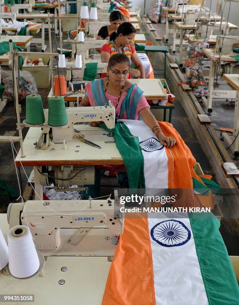 This photo taken on May 9, 2018 shows employees of Khadi Gramodyog Samyukta Sangh stitching together an Indian national flag at the Indian National...