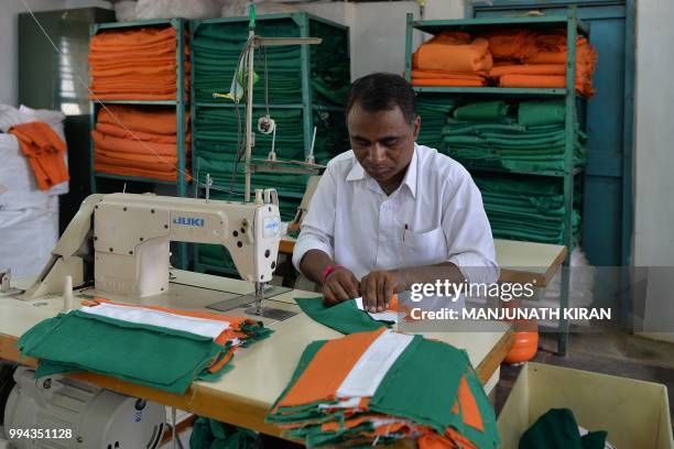 This photo taken on May 9, 2018 shows an employee of Khadi Gramodyog Samyukta Sangh stitching together an Indian national flag at the Indian National...