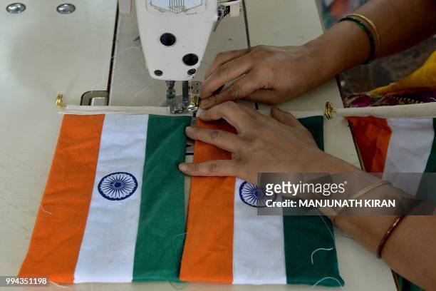 This photo taken on May 9, 2018 shows an employee of Khadi Gramodyog Samyukta Sangh stitching together an Indian national flag at the Indian National...