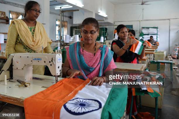 This photo taken on May 9, 2018 shows employees of Khadi Gramodyog Samyukta Sangh stitching together an Indian national flag at the Indian National...