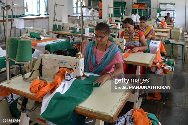 This photo taken on May 9, 2018 shows employees of Khadi Gramodyog Samyukta Sangh stitching together an Indian national flag at the Indian National...