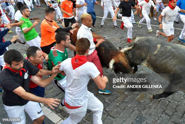 Participants run next to Cebada Gago fighting bulls on the third day of the San Fermin bull run festival in Pamplona, northern Spain on July 9, 2018....