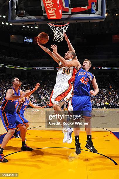 Stephen Curry of the Golden State Warriors shoots a layup against Danilo Gallinari and David Lee of the New York Knicks during the game at Oracle...