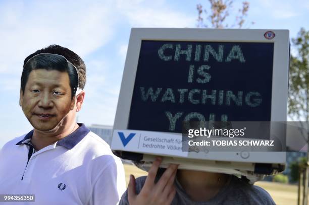 Activists of the 'Society for Threatened Peoples' demonstrate wearing masks of Chinese President Xi Jinping and a computer monitor reading 'China is...