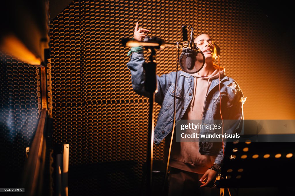Young hipster rap music singer recording song in music studio