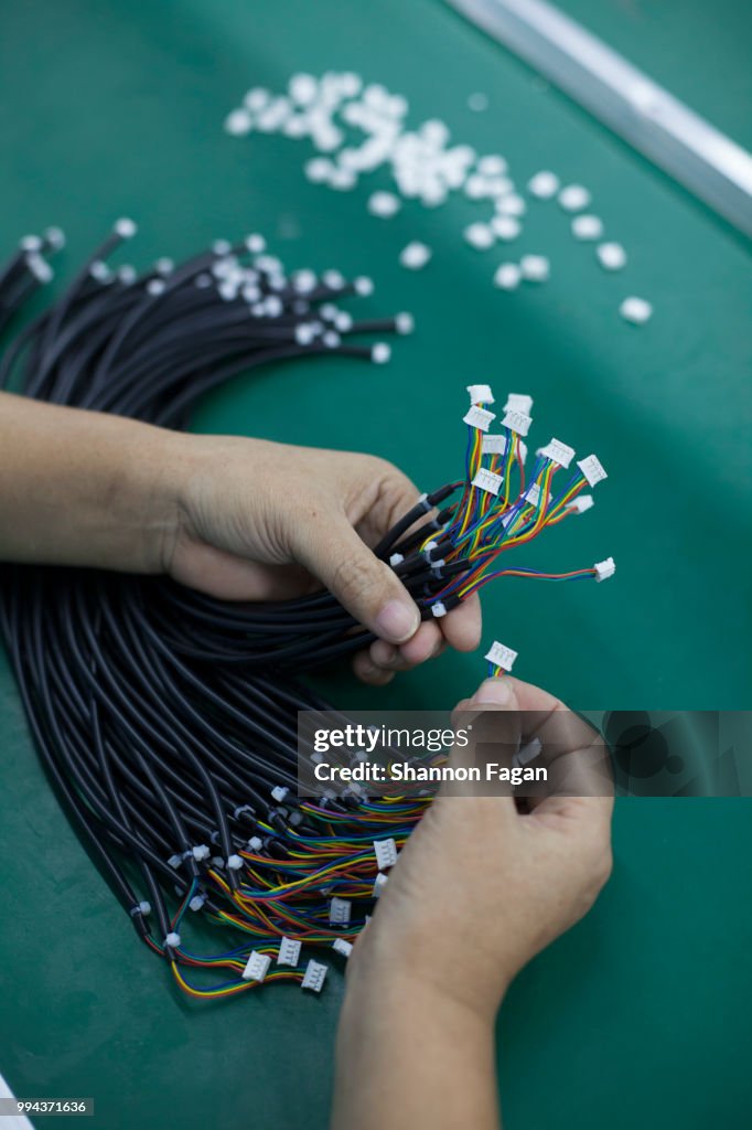 Hands of worker with electrical cords at an electronics factory in Dongguan, China