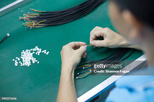 hands of worker with electrical cords at an electronics factory in dongguan, china - callus stock-fotos und bilder