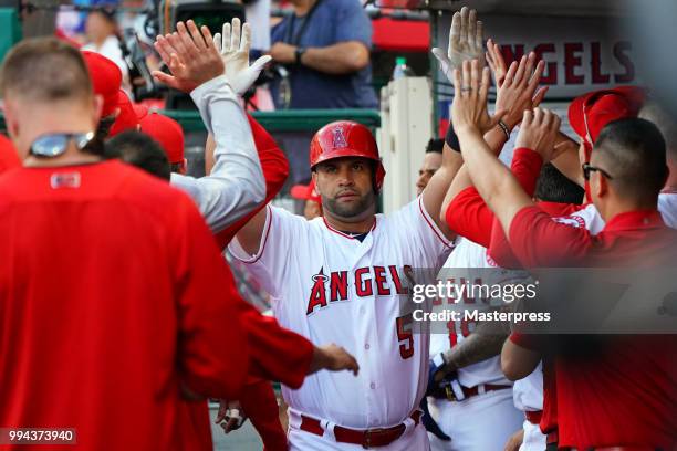 Albert Pujols of the Los Angeles Angels of Anaheim gets high fives after he hits a solo home run during the MLB game against the Los Angeles Dodgers...