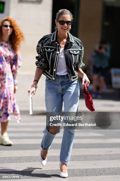 Helena Bordon wears a jacket with shiny embroidery, a white top, ripped jeans, a bag, outside Elie Saab, during Paris Fashion Week Haute Couture Fall...