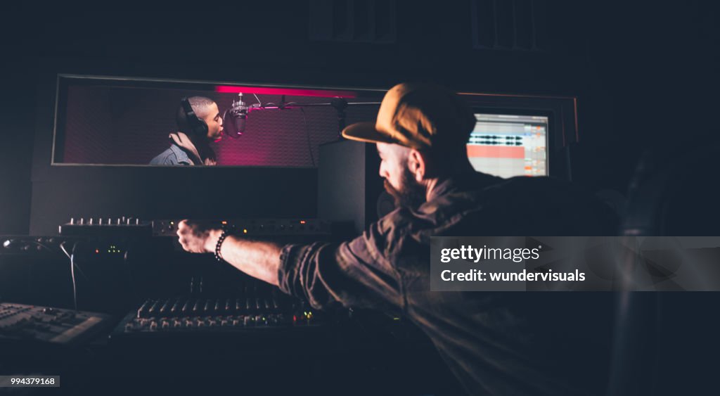 Hipster singer and music producer recording songs in music studio