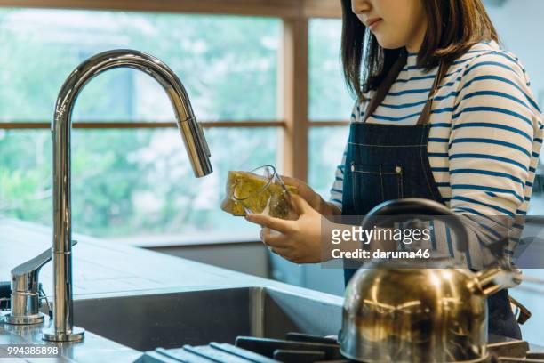 young woman washing the glass in the kitchen. - kitchen porter stock pictures, royalty-free photos & images