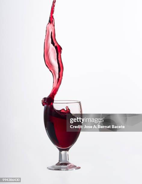 red wine splashing in glass in front of white background - kurzzeitfotografie stock-fotos und bilder