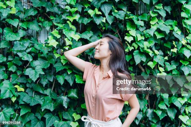 frau stand vor einer grünen wand. - asiatischer volksstamm stock-fotos und bilder
