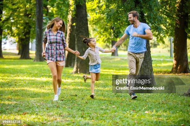 spielerische familie im park ausgeführt werden, während die hand in hand - emir memedovski stock-fotos und bilder