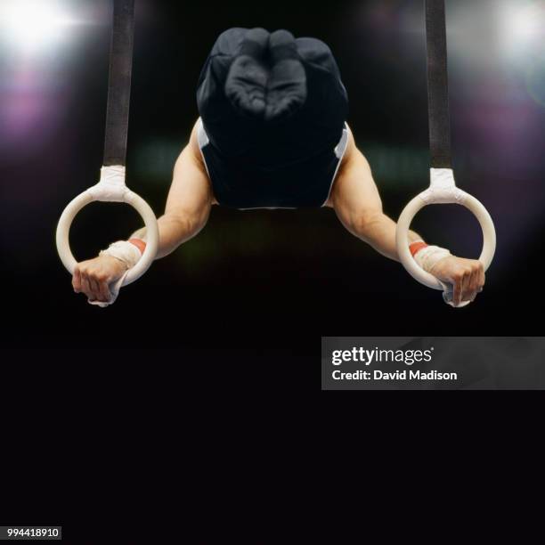 gymnast performing on rings - gymnastics equipment stock pictures, royalty-free photos & images