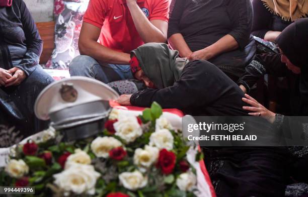The mother of killed Tunisian police officer Sgt. Arbi Guizani reacts as she mourns over his coffin in their home in the capital Tunis' northwestern...