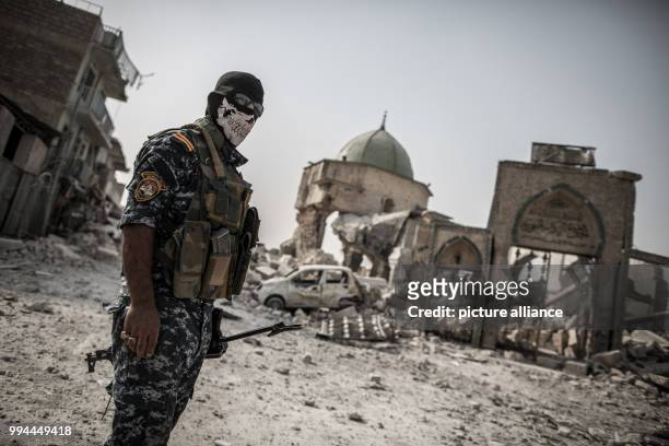 An Iraqi police man stands at the remains of the Al-Nuri mosque, where the Islamic State caliphate was proclaimed, in the old city of Mosul, Iraq, 21...