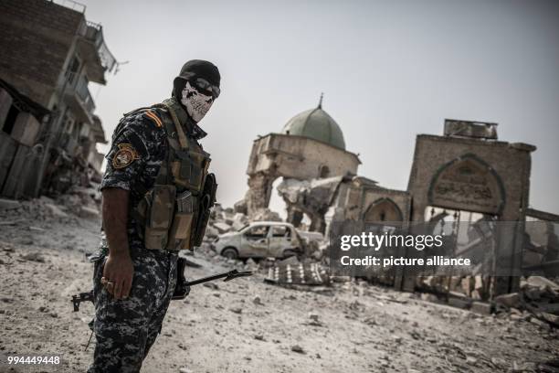 An Iraqi police man stands at the remains of the Al-Nuri mosque, where the Islamic State caliphate was proclaimed, in the old city of Mosul, Iraq, 21...