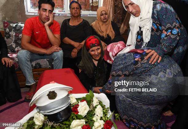 The mother of killed Tunisian police officer Sgt. Arbi Guizani reacts as she mourns over his coffin in their home in the capital Tunis' northwestern...