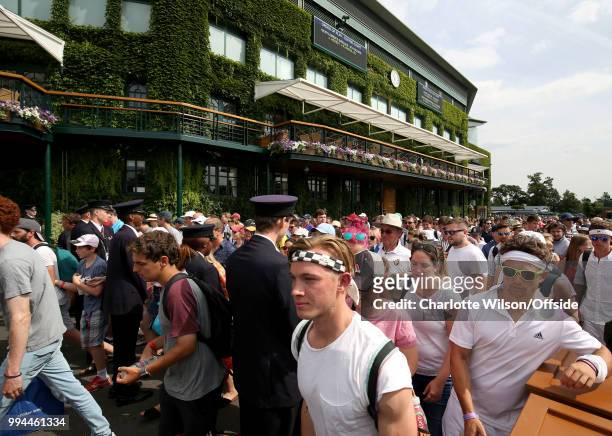 Crowd of spectators makes their way into the grounds after being lead in by security at All England Lawn Tennis and Croquet Club on July 9, 2018 in...