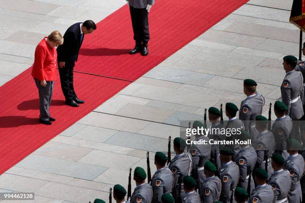 German Chancellor Angela Merkel and Chinese Premier Li Keqiang bow to the honor guard during the welcome ceremony at the Chancellery on July 9, 2018...