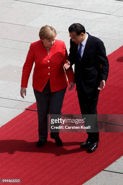 German Chancellor Angela Merkel and Chinese Premier Li Keqiang talk as they walk among the honor guard during the welcome ceremony at the Chancellery...