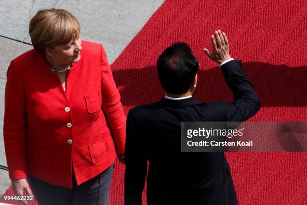 Chinese Premier Li Keqiang waves to supporters after he walked among the guard honeur guard honneur with German Chancellor Angela Merkel at the...